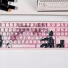 Gros plan d'un clavier mécanique rose avec des touches Raven Sakura et un design en silhouette noire.