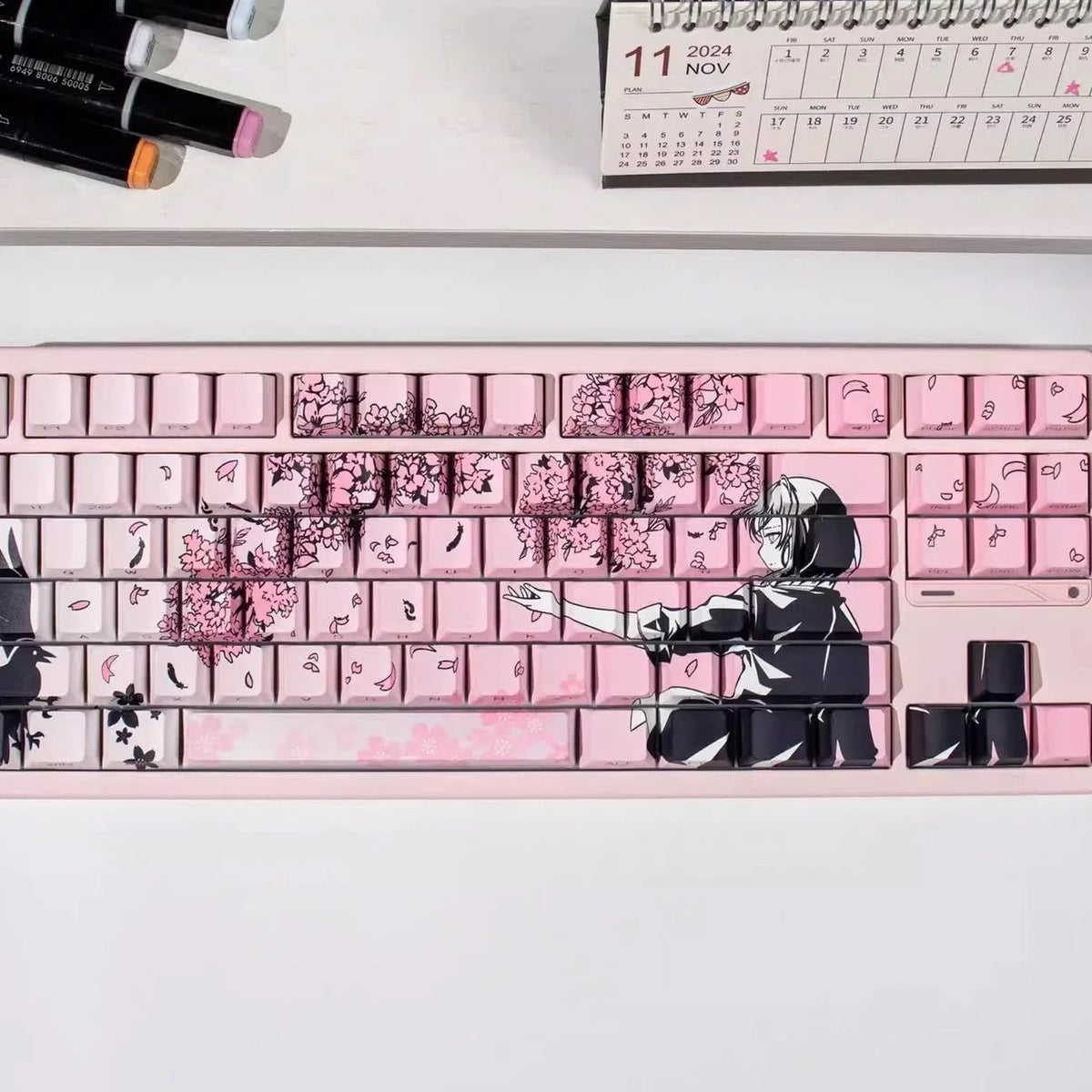 Gros plan d'un clavier mécanique rose avec des touches Raven Sakura et un design en silhouette noire.