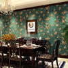 A richly decorated dining room featuring dark wood furniture and a teal floral wallpaper with gold accents.