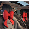 Red butterfly bow tie neck pillow with a textured cover shown in a car interior.