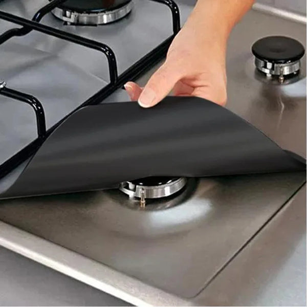 Une main place un protecteur de brûleur en silicone noir sur une grille de cuisinière.