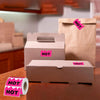 A cardboard box of pink stickers labeled HOT is shown next to a brown paper bag and a roll of pink stickers.