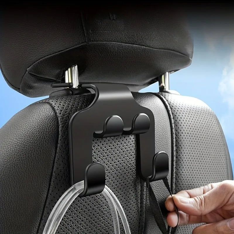 A black phone holder hook is being attached to a car back seat fabric using a clear plastic clip.