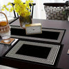 A set of black and white geometric table runners and placemats with a gold-framed clock on a dark table.