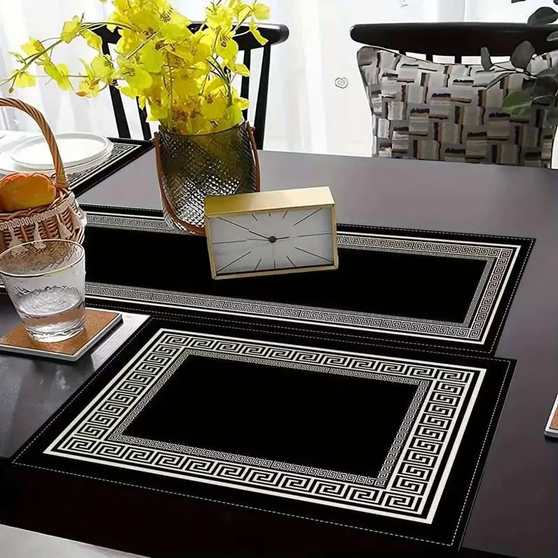 A set of black and white geometric table runners and placemats with a gold-framed clock on a dark table.