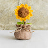 Handcrafted crochet sunflower with green leaves growing out of a burlap sack