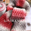 A close-up of a knitted scarf featuring a red and gray gradient pattern.