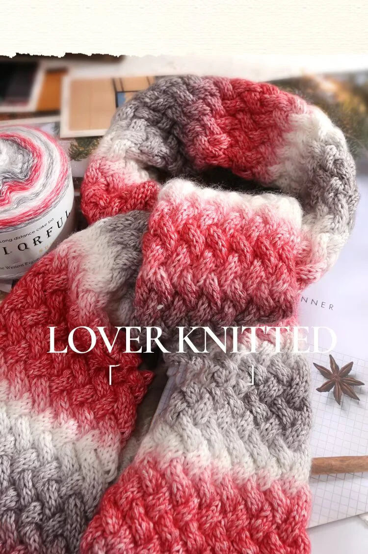 A close-up of a knitted scarf featuring a red and gray gradient pattern.