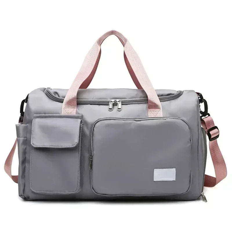 A gray travel duffel bag with pink straps and a separate shoe compartment pocket.