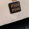 Nahaufnahme einer beigeen Make-up-Organizer-Tasche mit einem schwarzen Lederpatch und goldenen hebräischen Buchstaben.