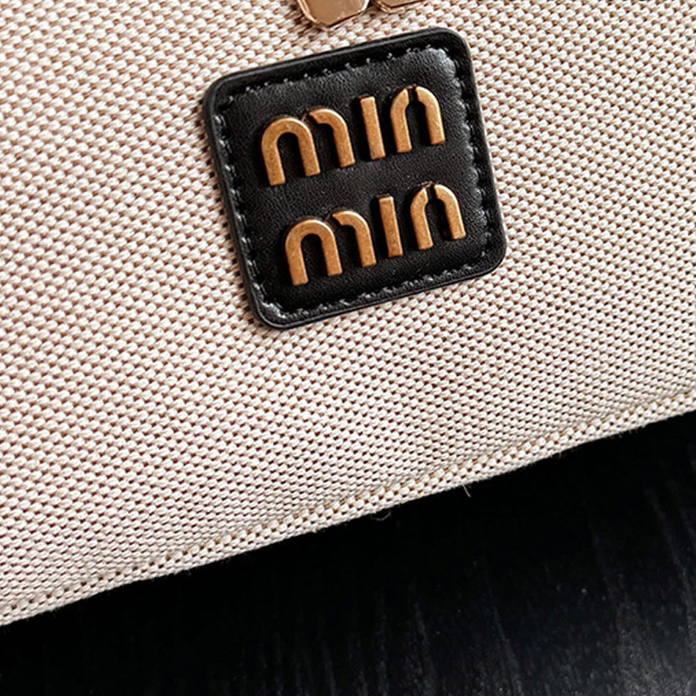 Nahaufnahme einer beigeen Make-up-Organizer-Tasche mit einem schwarzen Lederpatch und goldenen hebräischen Buchstaben.