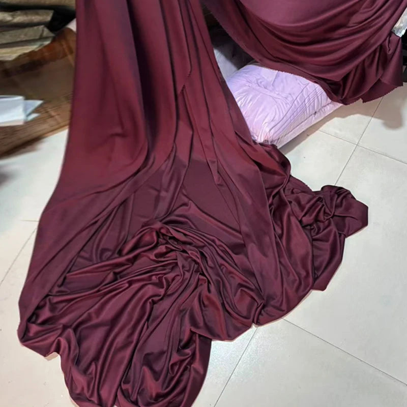 A drape of elegant burgundy stretch jersey fabric is shown in a flowing, gathered style.