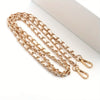 Gold-toned classic metal chain purse strap with a secure buckle laid on a white surface.