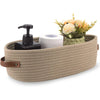 A woven cotton rope storage basket holding a black pump dispenser and a roll of white paper towels with an arrangement of ora