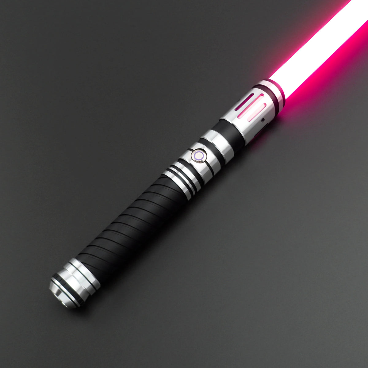 A close-up view of a Neo Pixel lightsaber with a glowing pink blade and black hilt against a dark background.