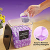 Hand pouring purple laundry detergent into a clear plastic storage box for easy removal.