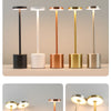 A row of six modern table lamps with varying metallic finishes and white stems displayed on a light gray surface.