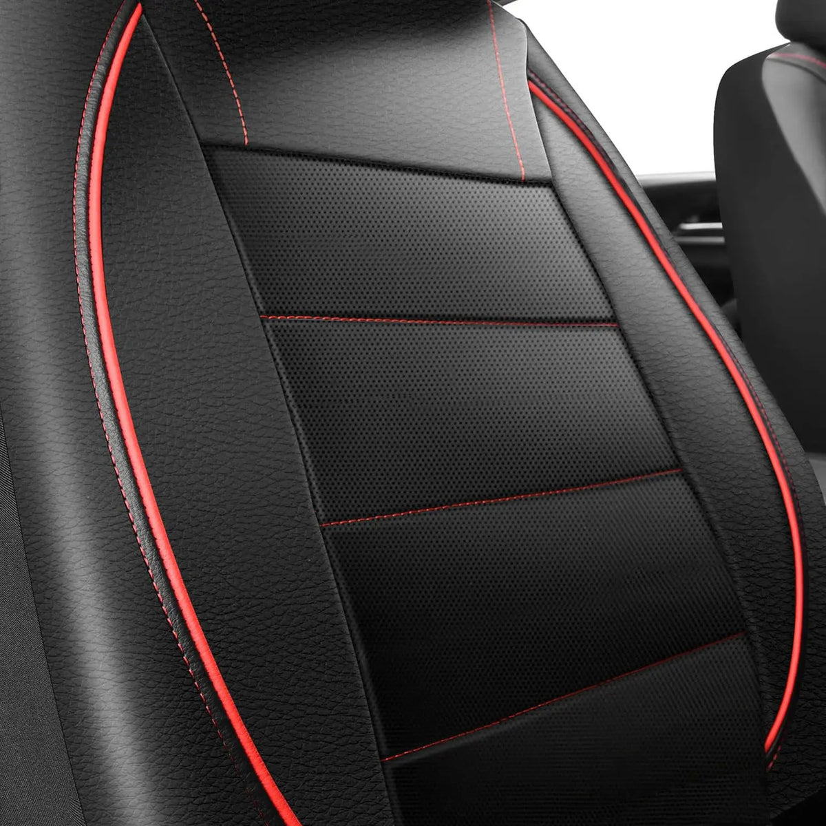 Close-up view of black leather car seat covers with red stitching and textured panels.