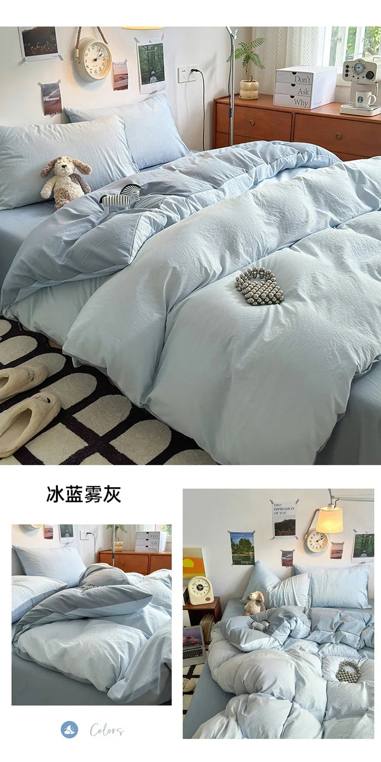 A set of four ultra-soft washed cotton duvet covers in a light blue or pale gray color displayed on a bed.