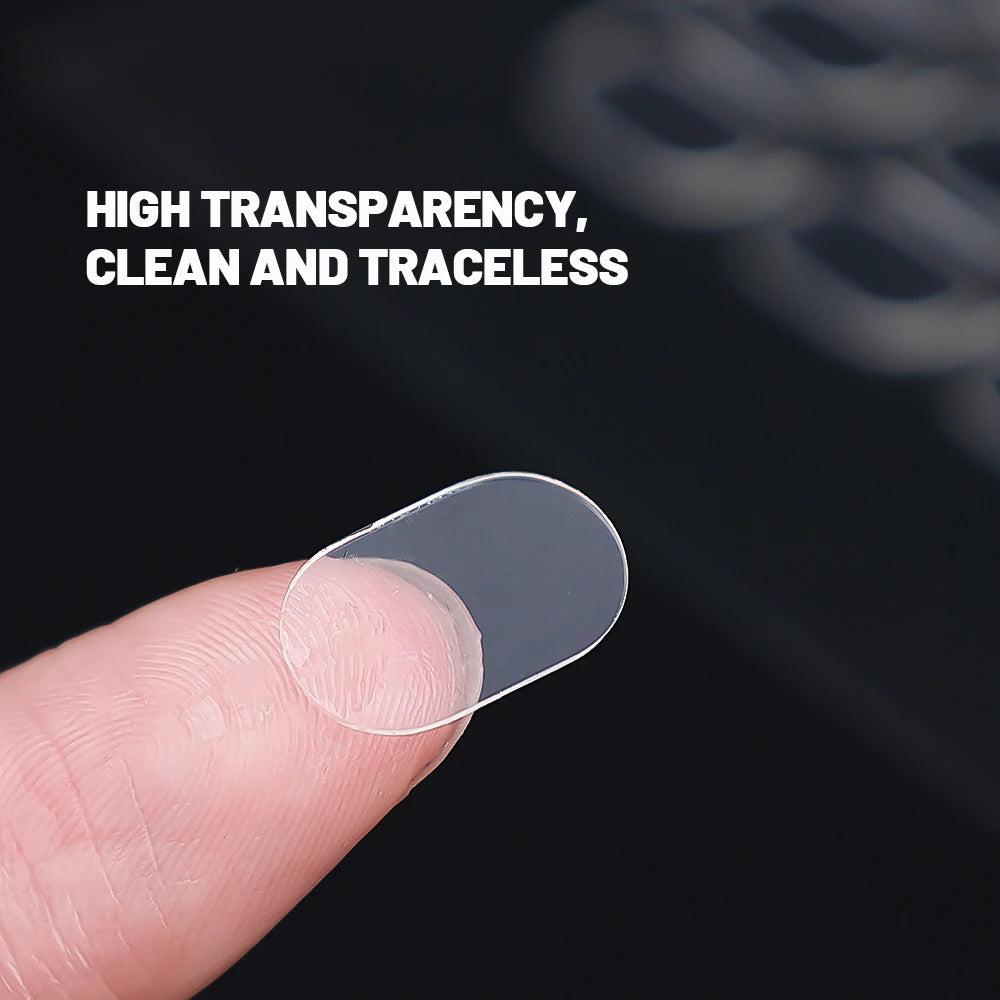 A hand holds a clear, double-sided adhesive patch against a dark background.