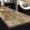 A kitchen countertop made of marble contact paper with a faucet, fruit, and rolled-up decorative paper visible.