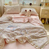 A pink floral washed cotton gauze summer quilt spread on a bed with a stuffed bear and a mug.