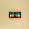 A black wooden tray filled with colorful wooden beads for a Montessori busy board set