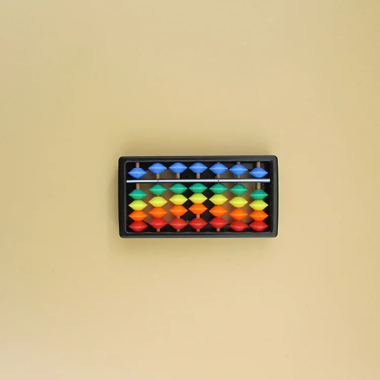 A black wooden tray filled with colorful wooden beads for a Montessori busy board set