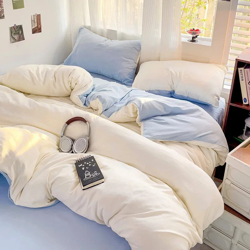 A bed with a solid cotton bedding set featuring light blue and cream colors, including a flat sheet, duvet cover, and pillows