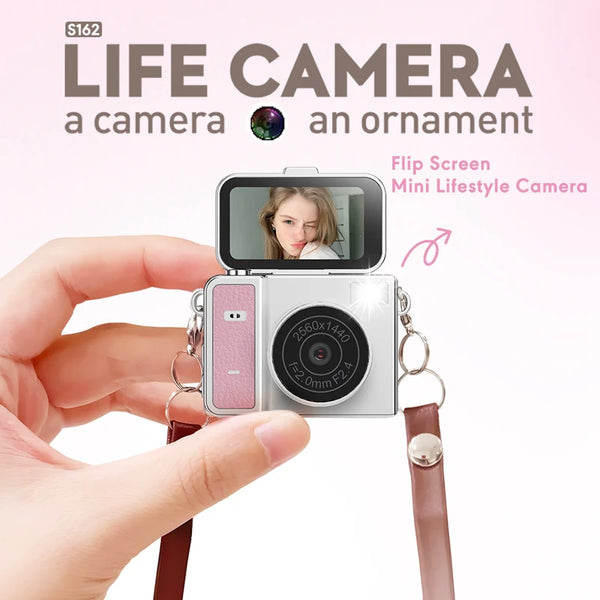يد تمسك بكاميرا Flip Screen Mini Lifestyle ذات جسم وردي وحزام بني.