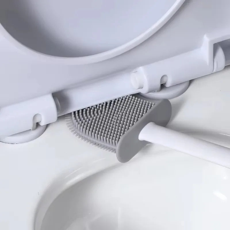 A white wall-mounted toilet brush set with a silicone head is shown above a white ceramic toilet bowl.