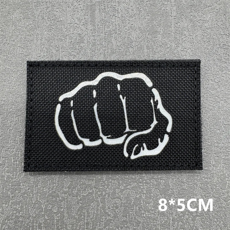 Black tactical patch featuring a white clenched fist design with hook and loop backing