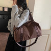 A woman holds a brown leopard print duffle bag with an adjustable strap against a light-colored wall.