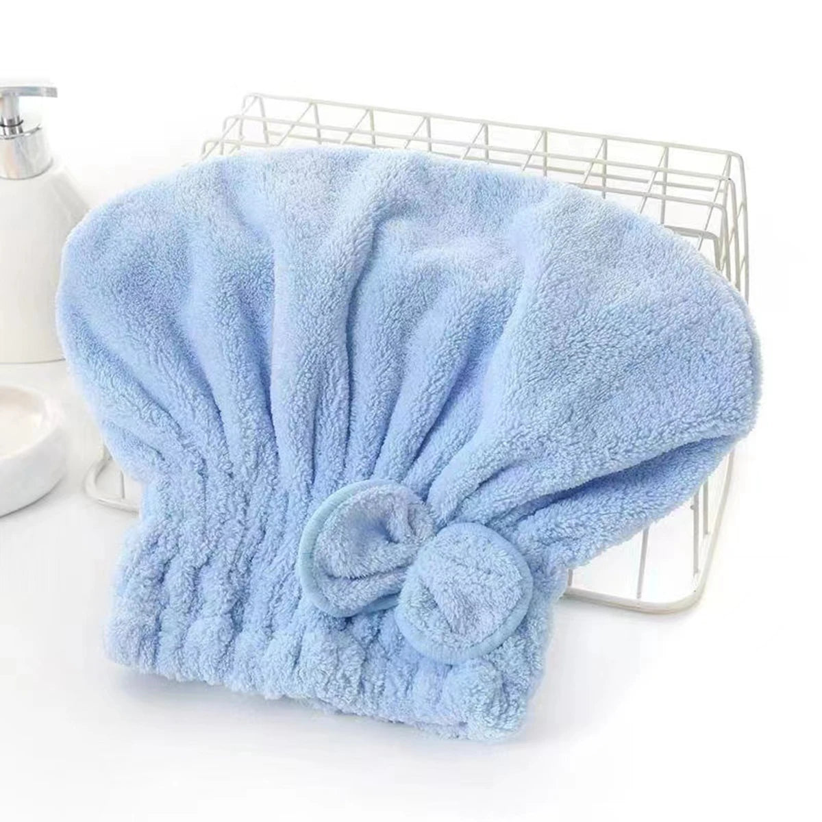 Light blue microfiber hair drying towel with a bow-knot head wrap placed on a wire rack.
