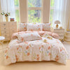 A light pink and white printed duvet cover set with matching pillowcases displayed on a bed in a bright room.