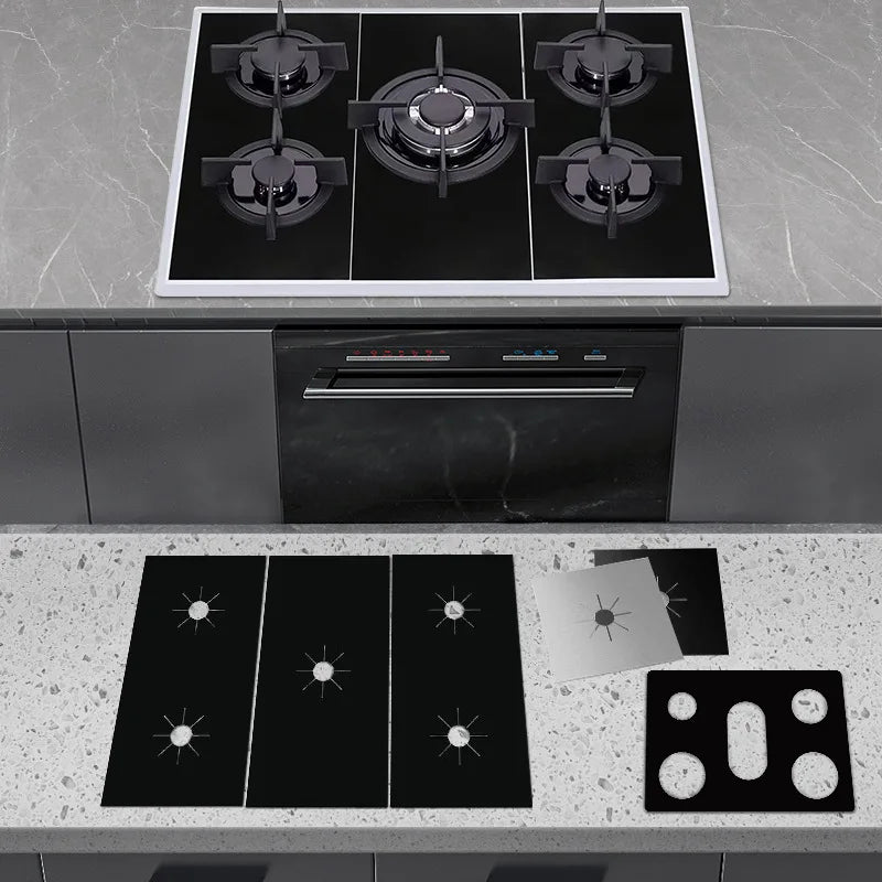 A kitchen setup showing a stovetop and a built-in oven, with several black reusable non-stick gas stove protector mats on the