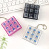 A set of tactile clicking keyboard fidget toys in pink and clear plastic are displayed next to a white keyboard.