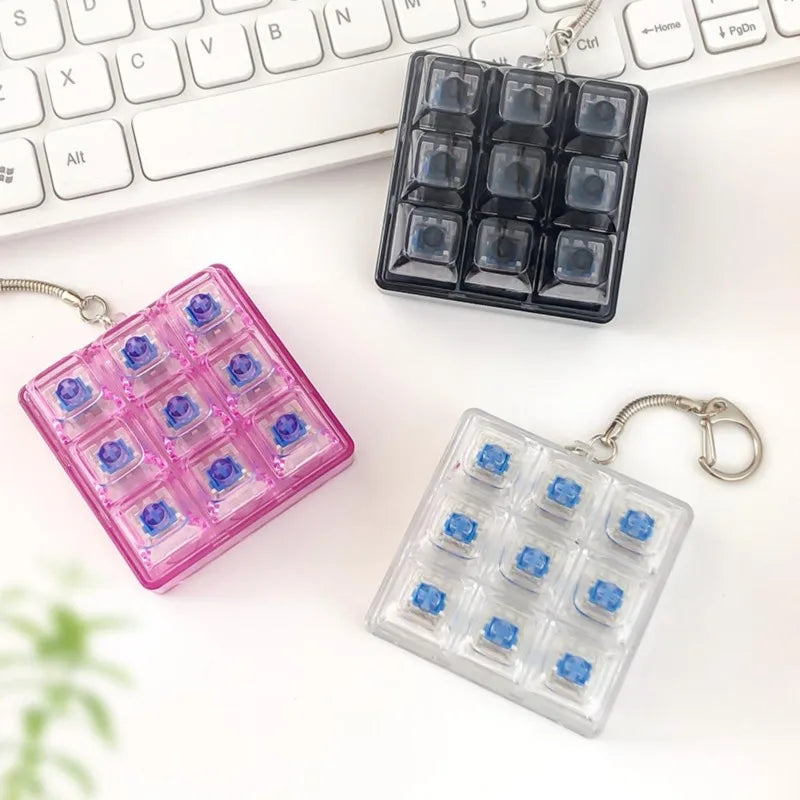 A set of tactile clicking keyboard fidget toys in pink and clear plastic are displayed next to a white keyboard.