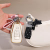 A hand holds a white PU leather bag with a black bow keychain featuring an O-shaped silver buckle.