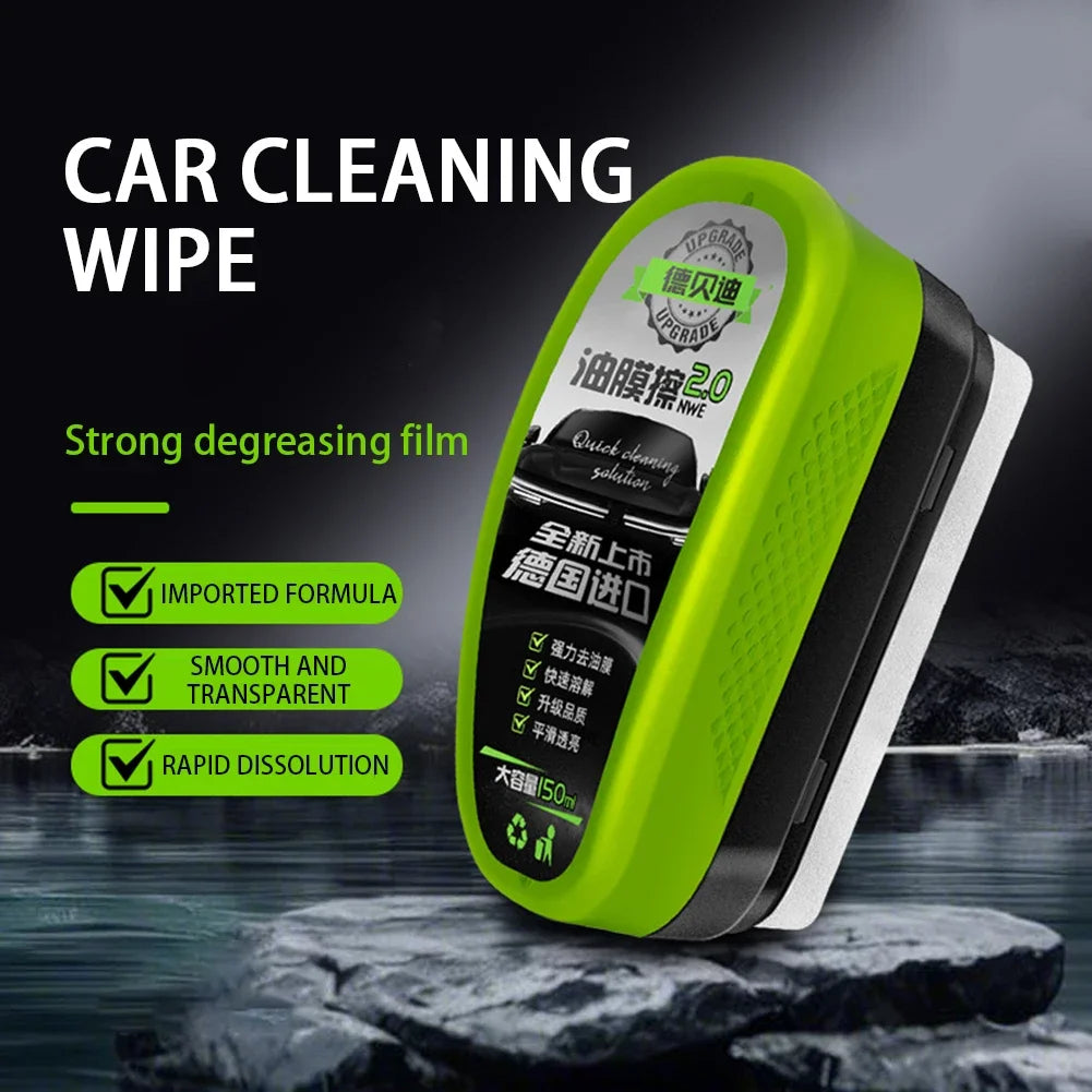 A bright green car cleaning wipe with a black handle is shown resting on dark rocks.