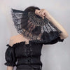 A black vintage lace folding hand fan with a decorative handle is held by a person.