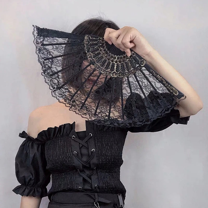 A black vintage lace folding hand fan with a decorative handle is held by a person.