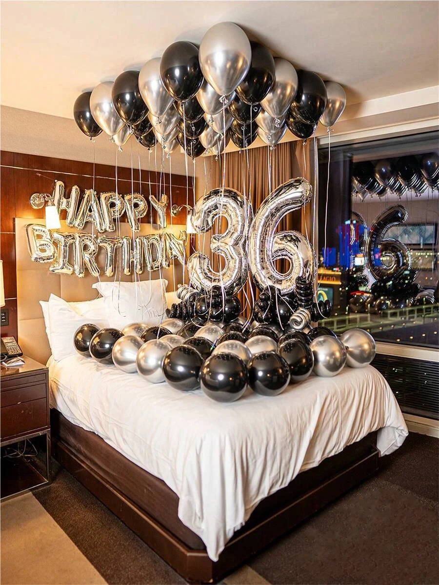 A celebratory balloon garland featuring silver and black balloons spelling out the number 36 above a bed.
