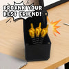 A black box containing several gold middle finger surprise items is shown on a wooden table.