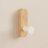 A light wood self-adhesive hook is mounted on a wall, used for entryway or bathroom organization.
