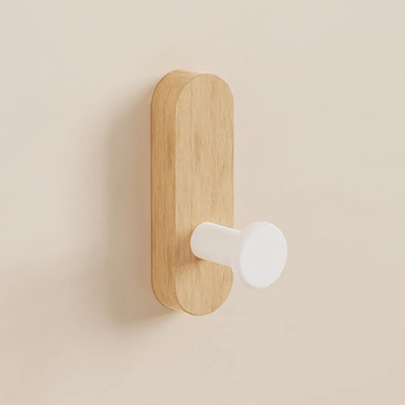 A light wood self-adhesive hook is mounted on a wall, used for entryway or bathroom organization.