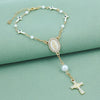 Gold rosary necklace with pearl beads and a white oval pendant featuring a cross charm