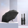 Black folding parasol or umbrella with a dark fabric canopy displayed on a white pedestal.