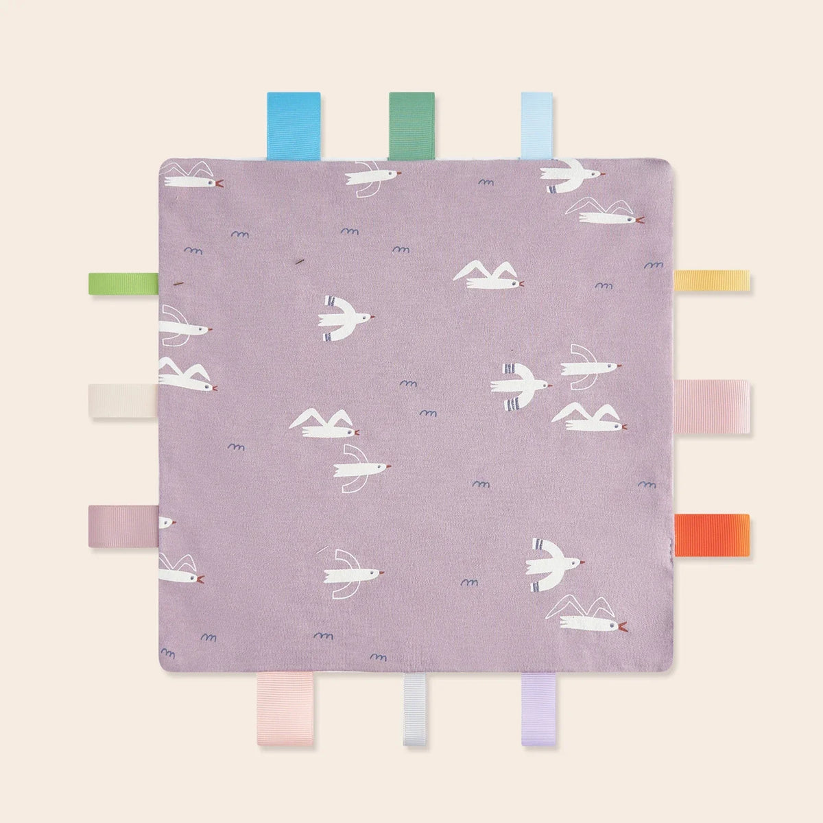 A purple baby sensory tag comfort blanket featuring white birds and soothing teether shapes.