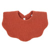 A terracotta orange knitted baby bib in a bandana style with a small white button closure.